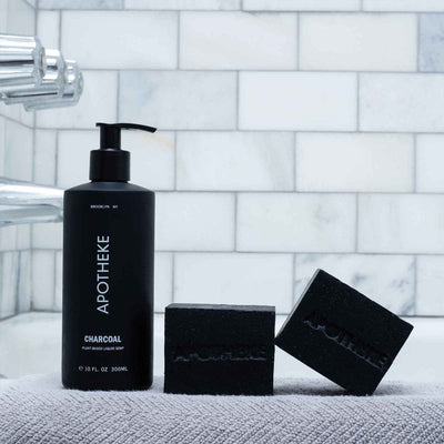 APOTHEKE Charcoal Liquid Soap bottle styled on a bathroom shower ledge with matching bar soap