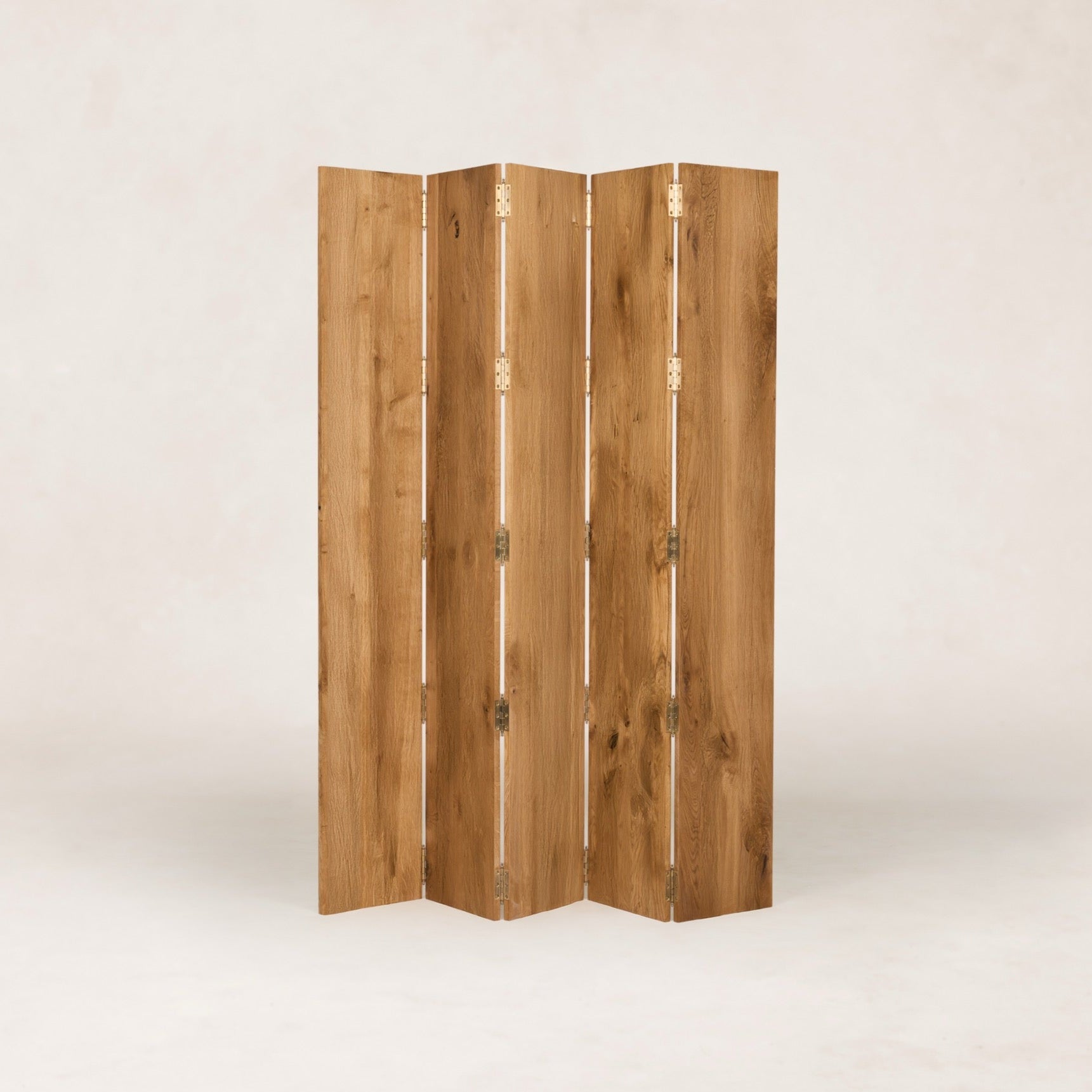 A four-panel folding screen made of natural wood with visible grain and brass hinges, standing upright against a light neutral studio background by House of Leon.