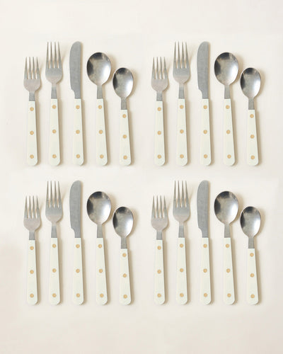 Two complete ivory-handled cutlery settings arranged in neat rows, showing polished stainless-steel utensils and warm cream handles with brass-toned rivets.