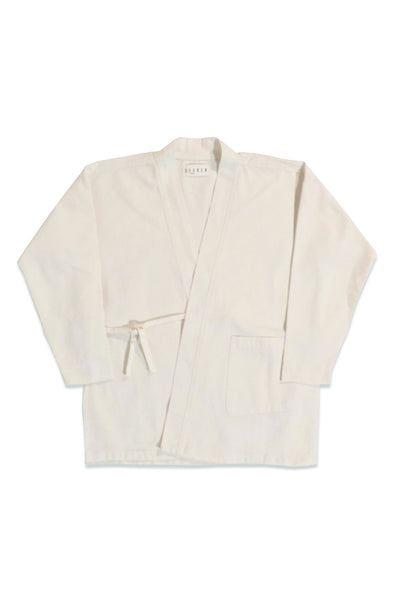 Front product view of the white GI wrap jacket with waist ties and patch pockets.