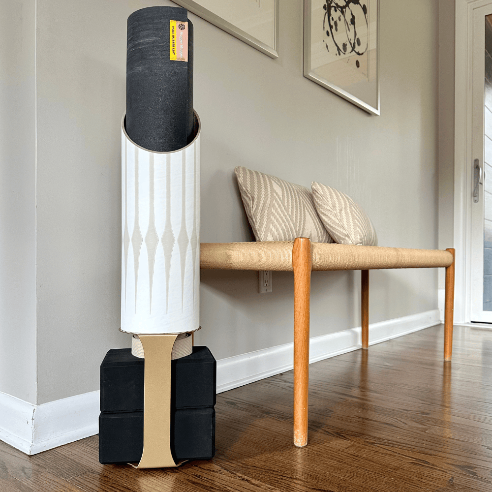 Gather tube holding a black mat on four black base blocks beside a woven bench.