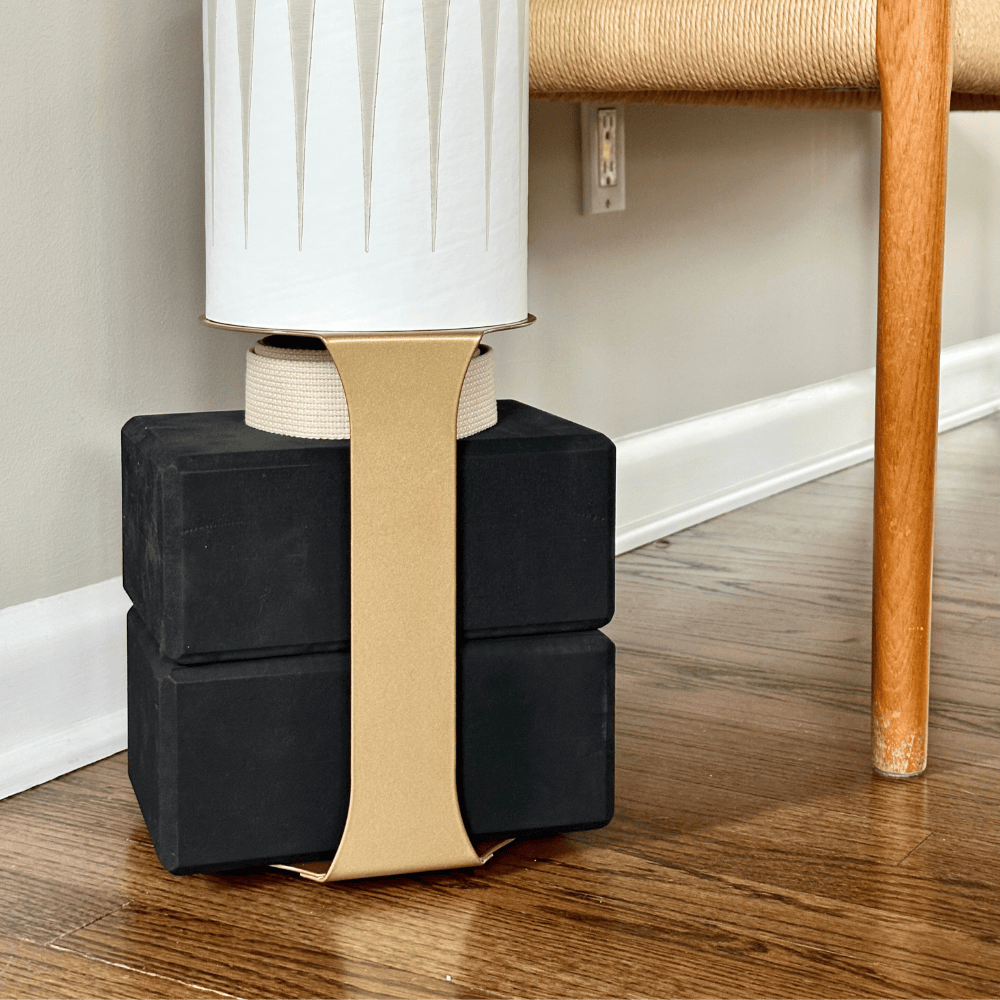 Close-up of four black base blocks secured beneath the tube with a wide tan support strap.
