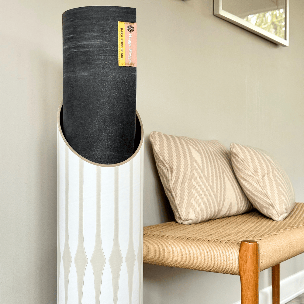 Close-up of the rolled black mat extending from the tube’s angled opening, highlighting the slim tan pattern on the white exterior.