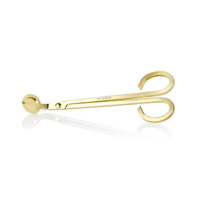 APOTHEKE gold wick trimmer with long handles, curved finger loops, and a round cutting head, displayed horizontally with a faint reflection on a white background.