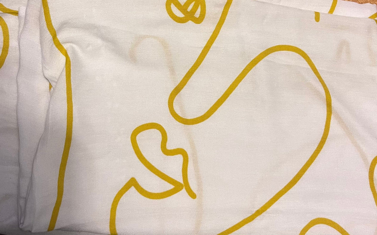 Village Thrive Faces Kimono, white rayon with mustard yellow line print, close-up fabric detail.