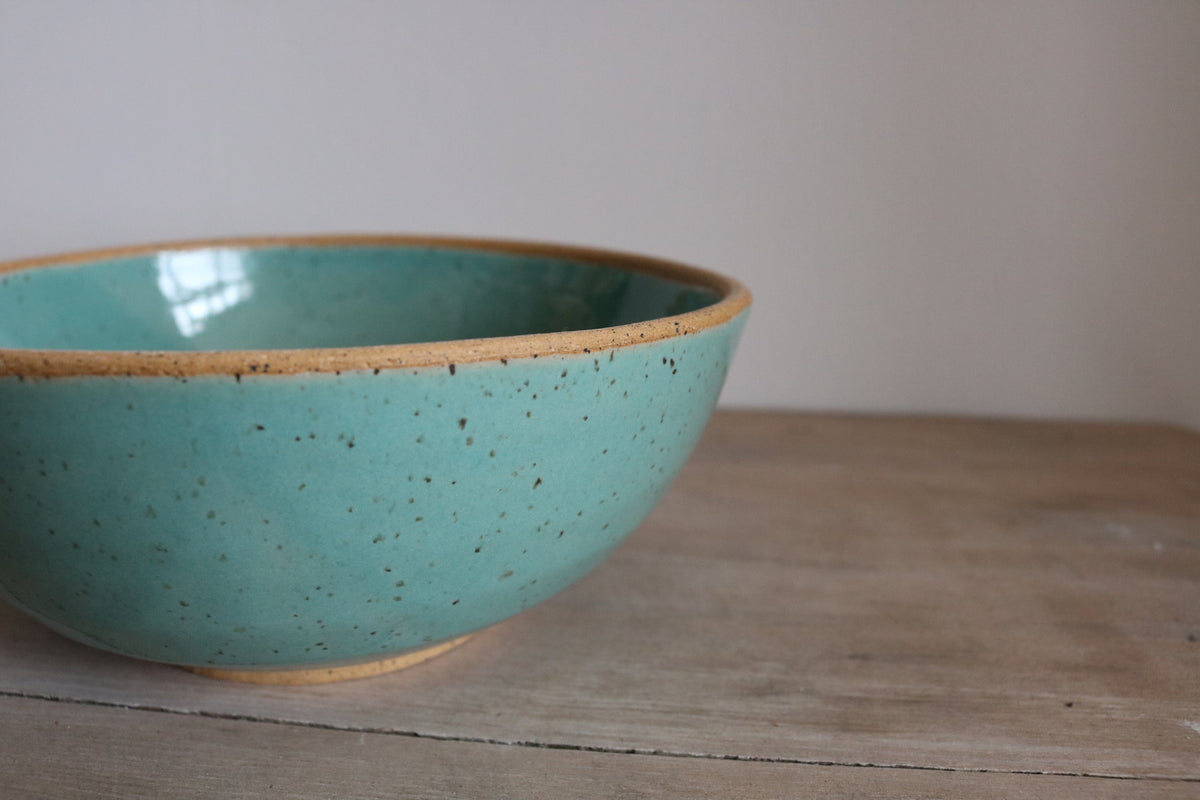Light teal handmade ceramic cereal bowl on wooden surface