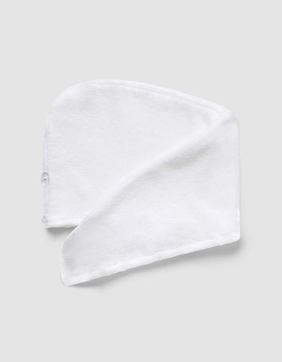 White hair towel displayed flat with one side folded diagonally, showing its curved shape, plush texture, and stitched edging.