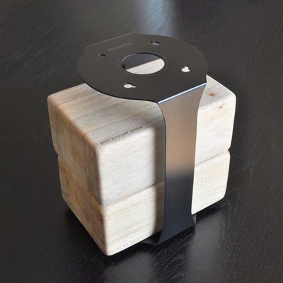 Black metal support strap wrapped around a four-block pale wood base, viewed from above.