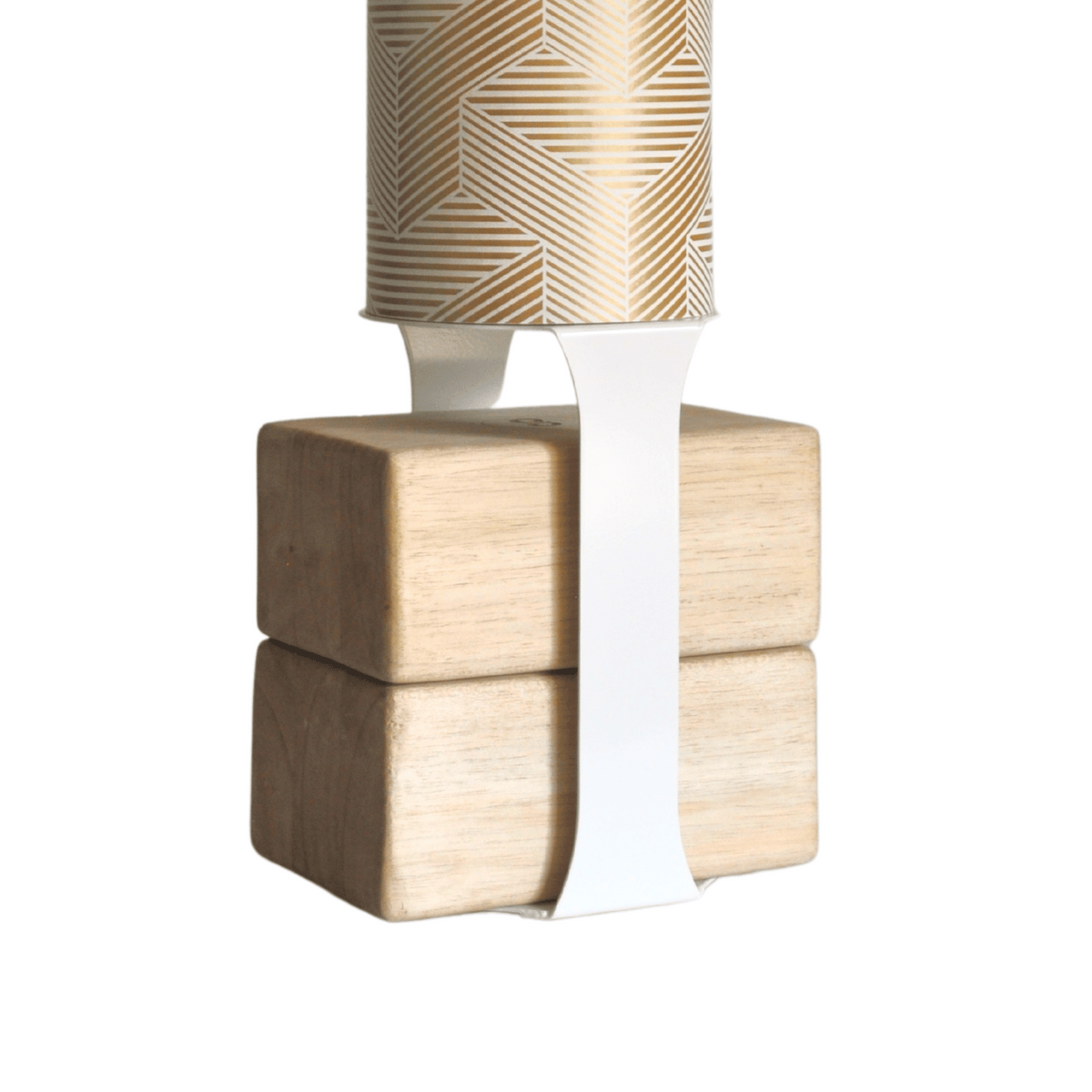 White support strap wrapped around four natural wood blocks beneath a gold-patterned Mache tube.