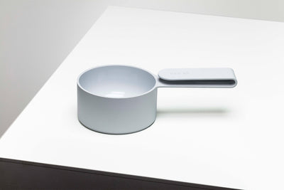 Pale blue-gray Mogo Scooper with a deep round measuring cup and short flat rectangular handle, displayed on a white tabletop.