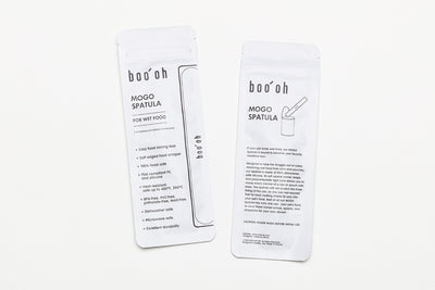 Two white Boo Oh storage pouches printed with product information for the Mogo Spoon and Mogo Spatula.