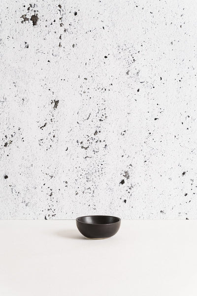 Stoneware bowl in Matte Black against textured concrete background
