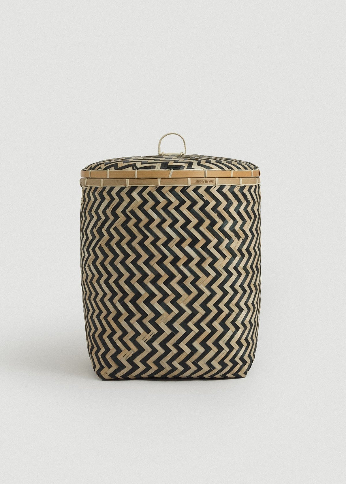 Large bamboo storage basket with a fitted lid, loop handle, and bold black-and-natural zigzag weave.