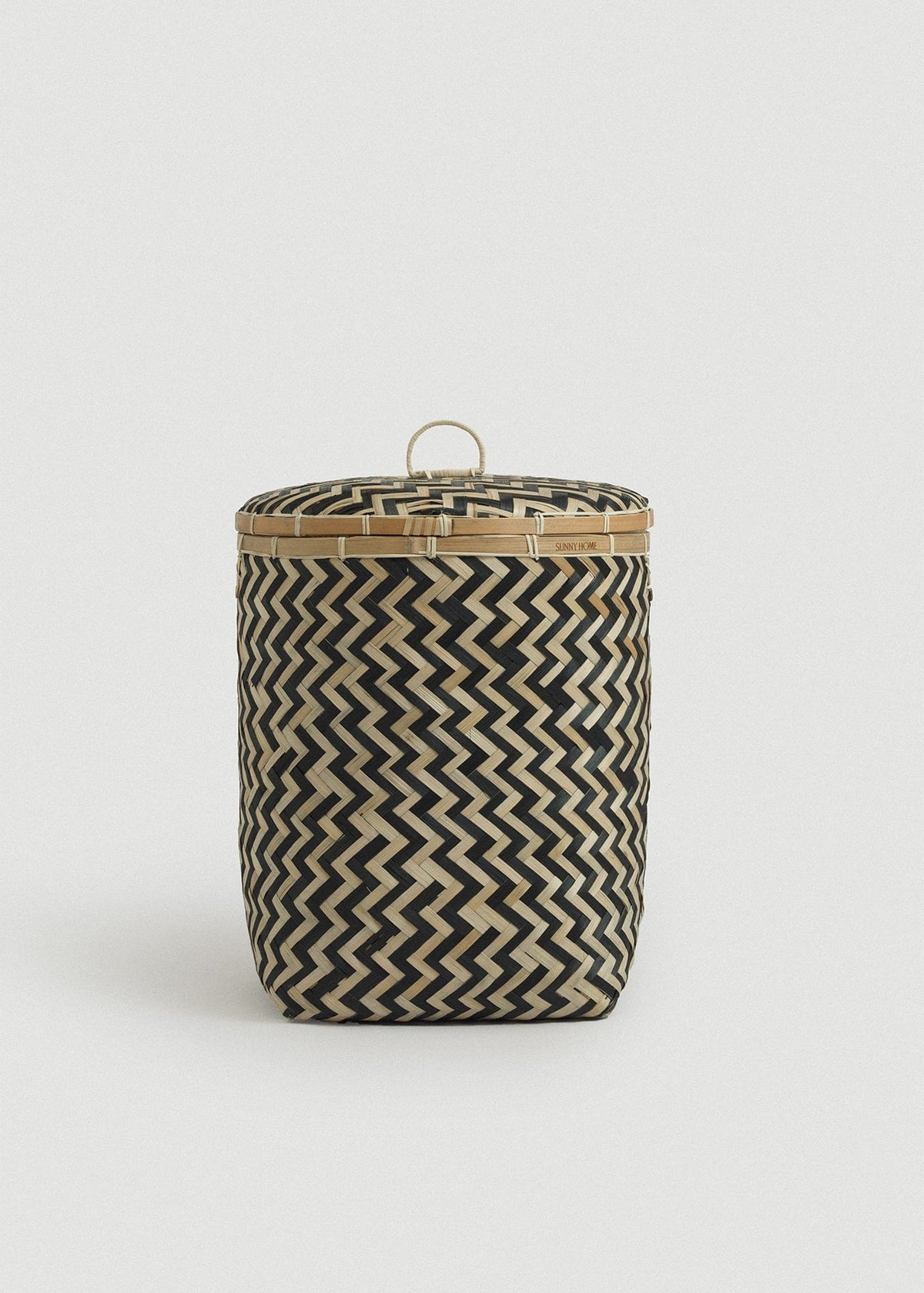 Tall lidded basket highlighting the tightly woven black-and-natural zigzag design.