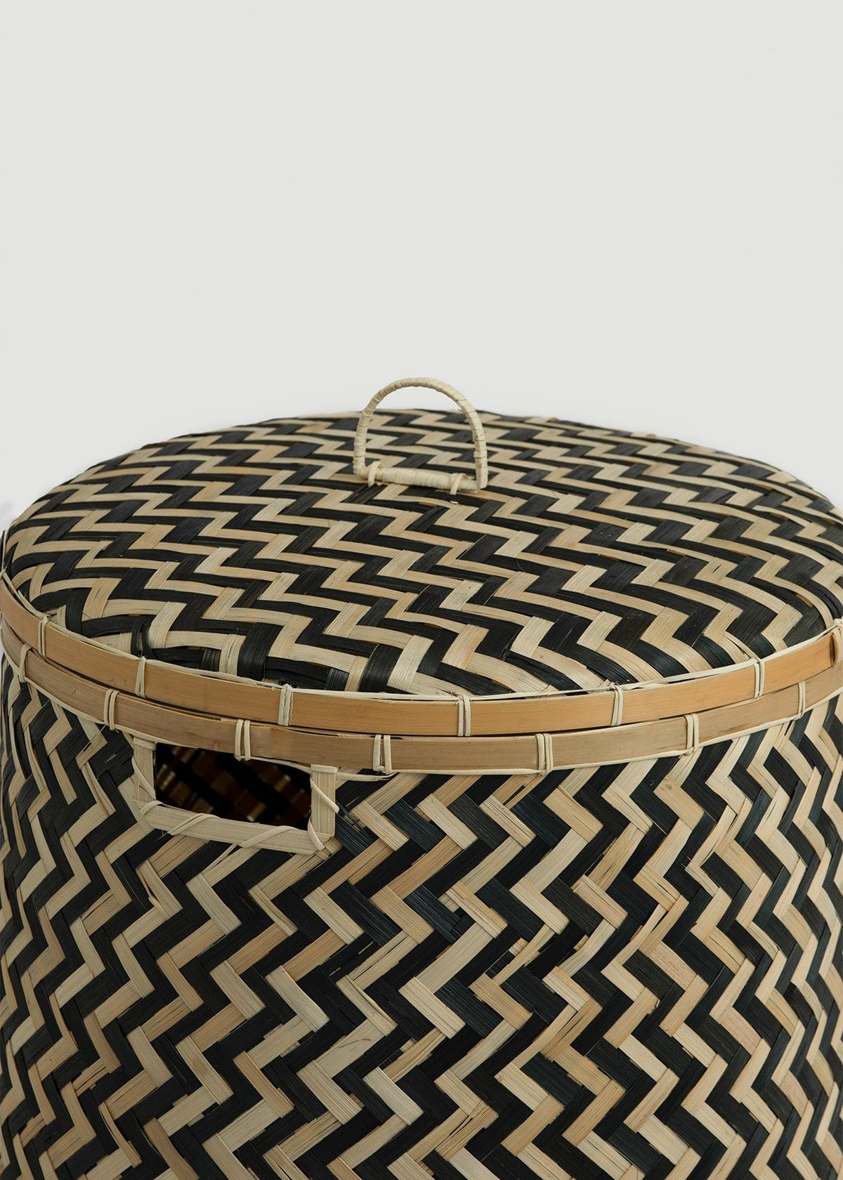 Close-up of the fitted lid, loop handle, reinforced bamboo rim, and chevron weave.