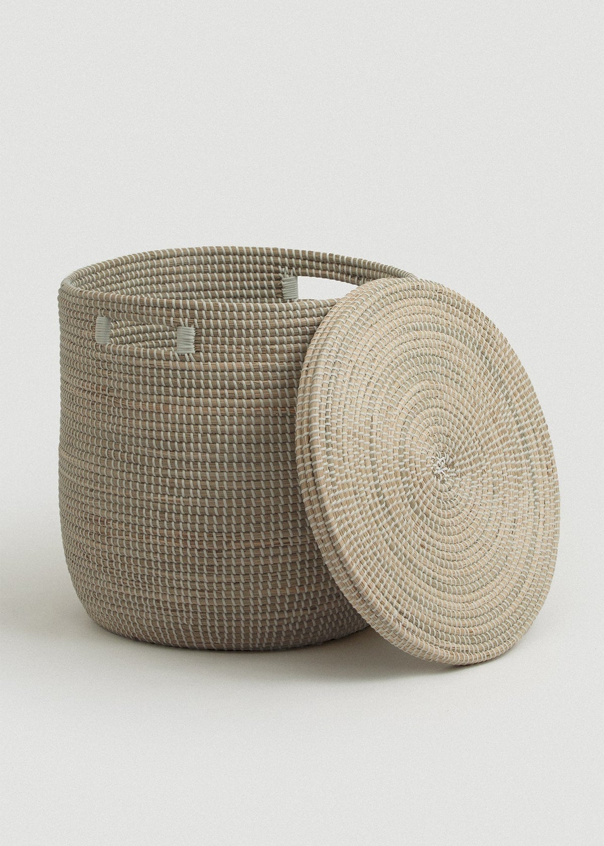 Open seagrass basket with the circular flat lid leaning against its side, revealing the roomy interior.