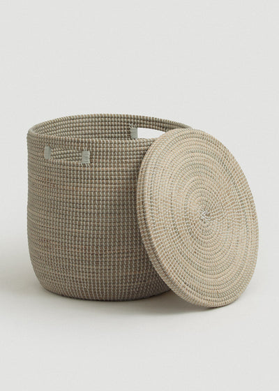 Open seagrass basket with the circular flat lid leaning against its side, revealing the roomy interior.