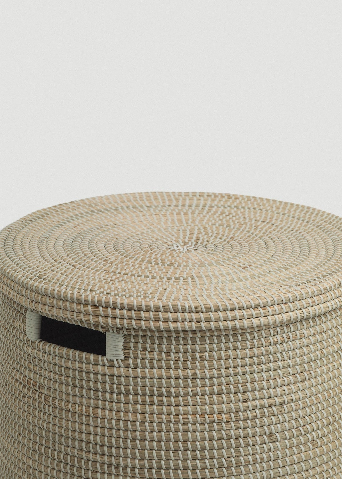Close-up of the spiral-woven lid, thick basket rim, and contrasting black handle.