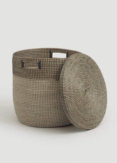 Open seagrass basket with the matching circular lid leaning against its side.
