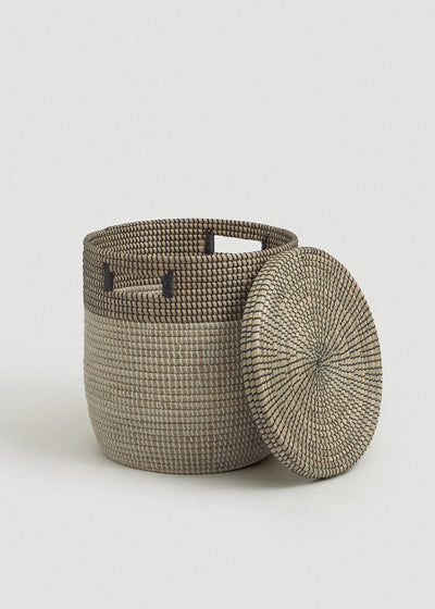 Open seagrass basket with the matching circular lid leaning against its side.