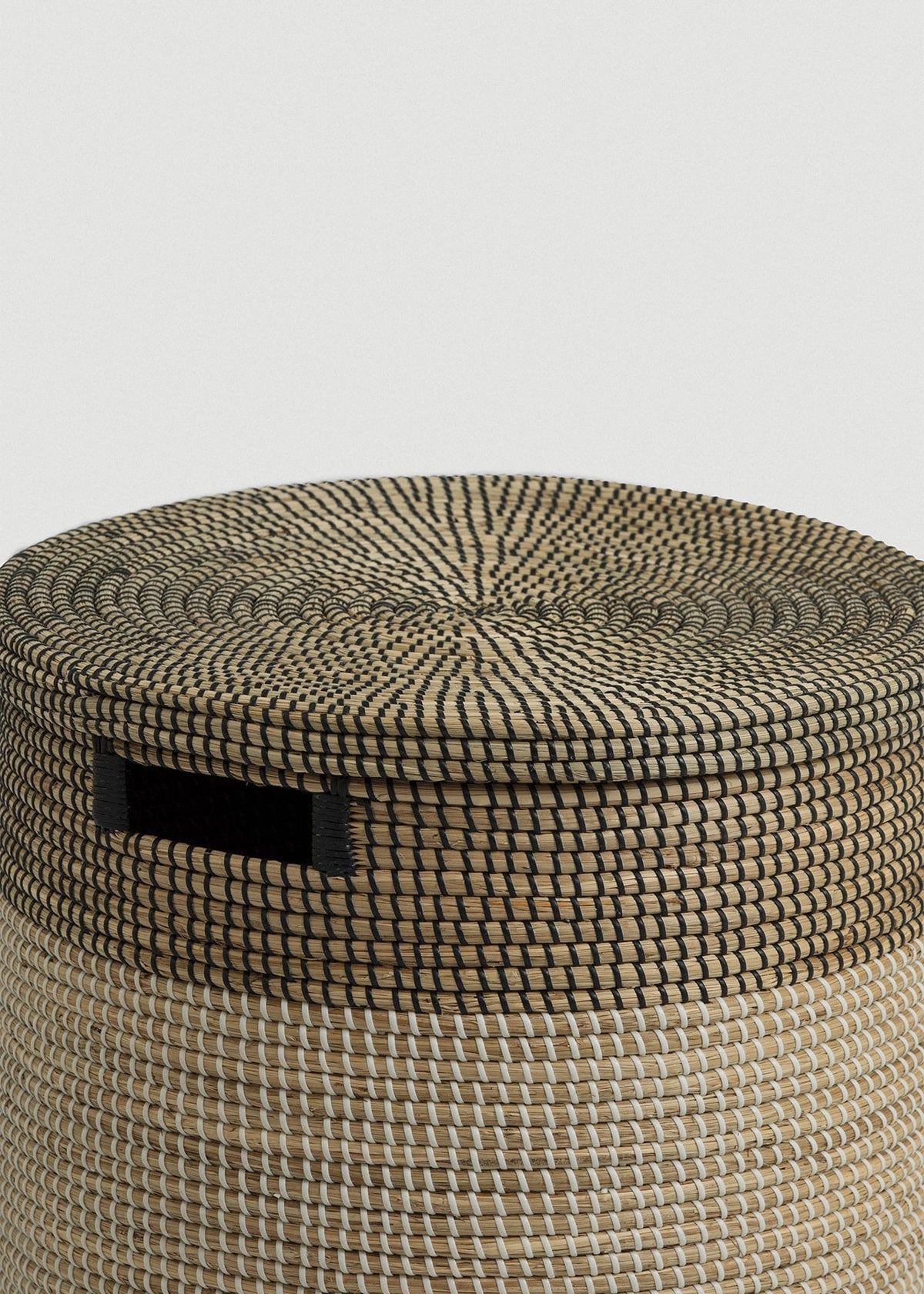 Close-up of the spiral-woven black-and-natural lid, dark upper band, and rectangular handle.