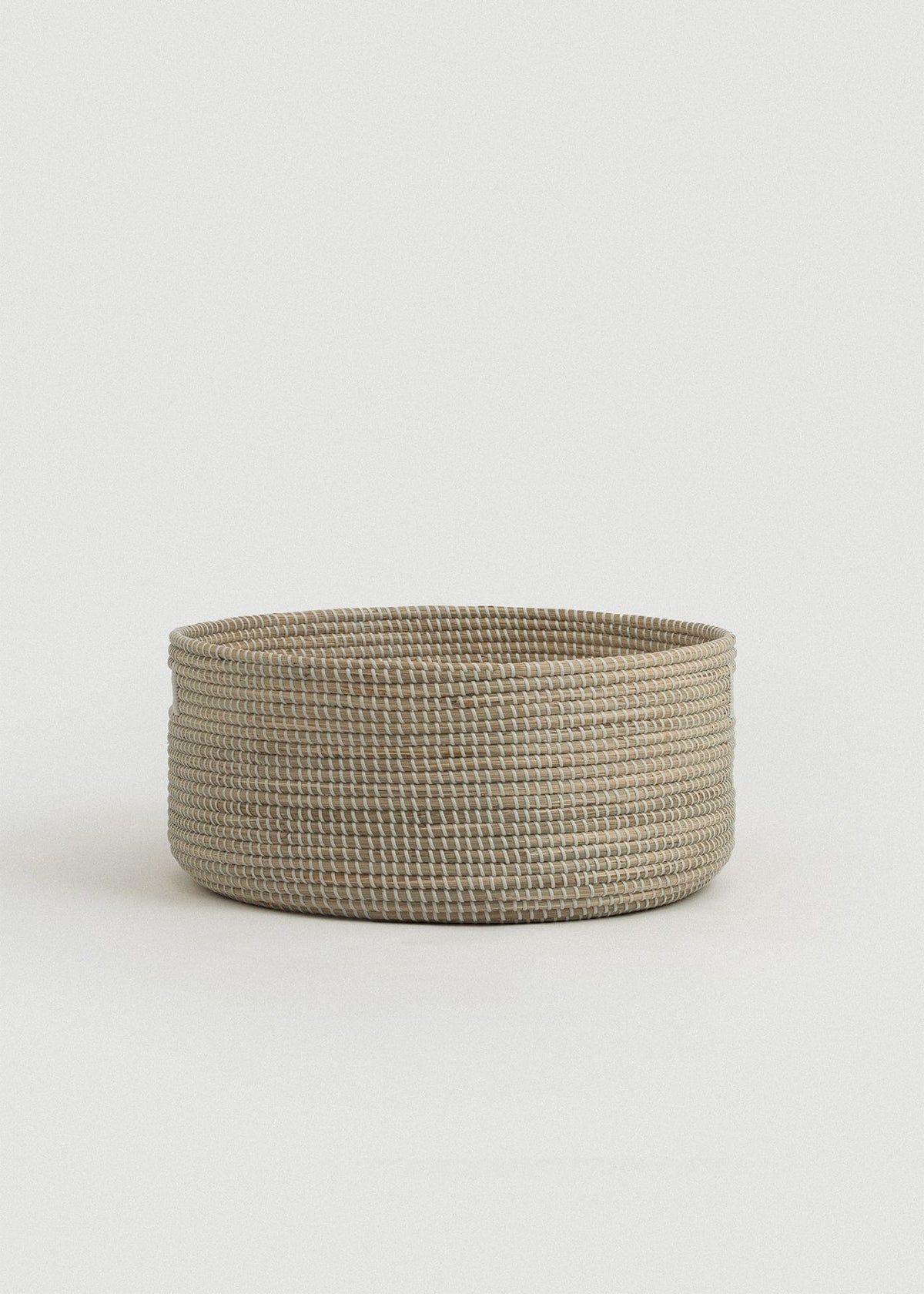 Side view of the Medina floor basket showing its wide, shallow shape and reinforced rim.