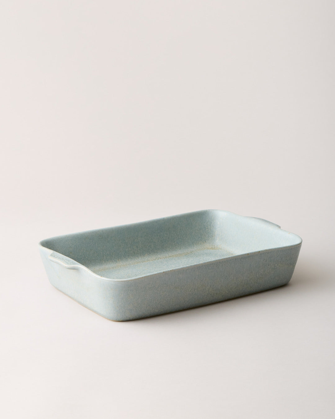 Empty blue-gray Fieldstone Baker shown alone from a low three-quarter angle, highlighting its shallow depth and softly curved rectangular shape.