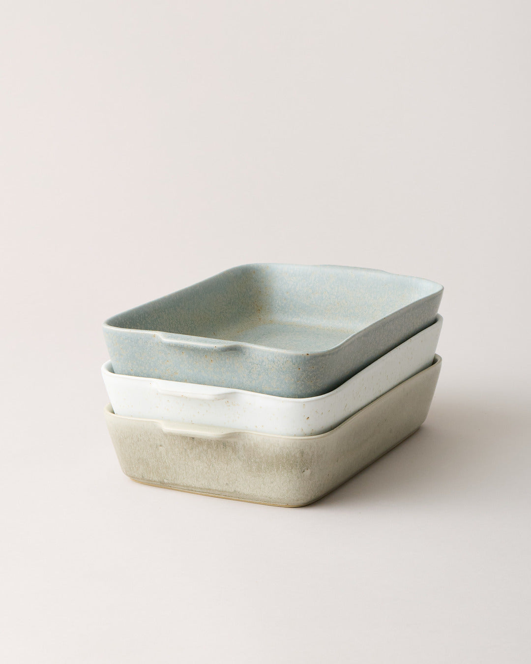 Blue-gray and warm stone Fieldstone Bakers stacked together, showing their compact rectangular shape, softly rounded corners, and contrasting glazes.