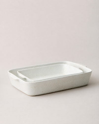 Two speckled white Fieldstone Bakers nested together in different sizes, showing their matching rounded rectangular forms and side handles.