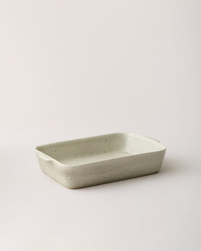Empty warm stone Fieldstone Baker with a softly mottled beige-gray glaze, shallow interior, and gently flared rim.