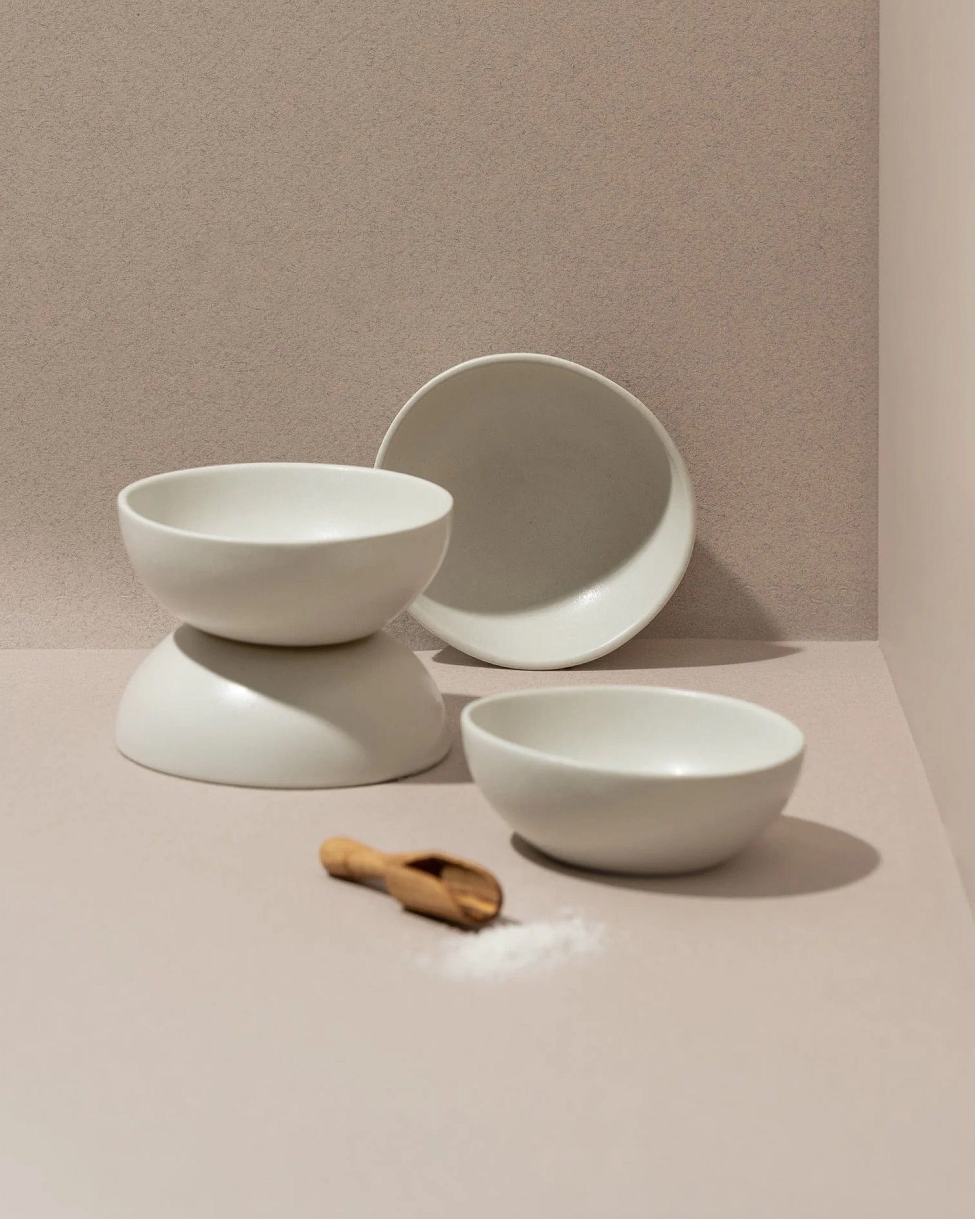 Stoneware bowls in Matte White stacked with wood spoon on neutral background