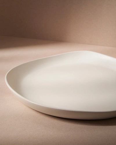 Stoneware round serving platter in Matte White angled view on warm-toned background