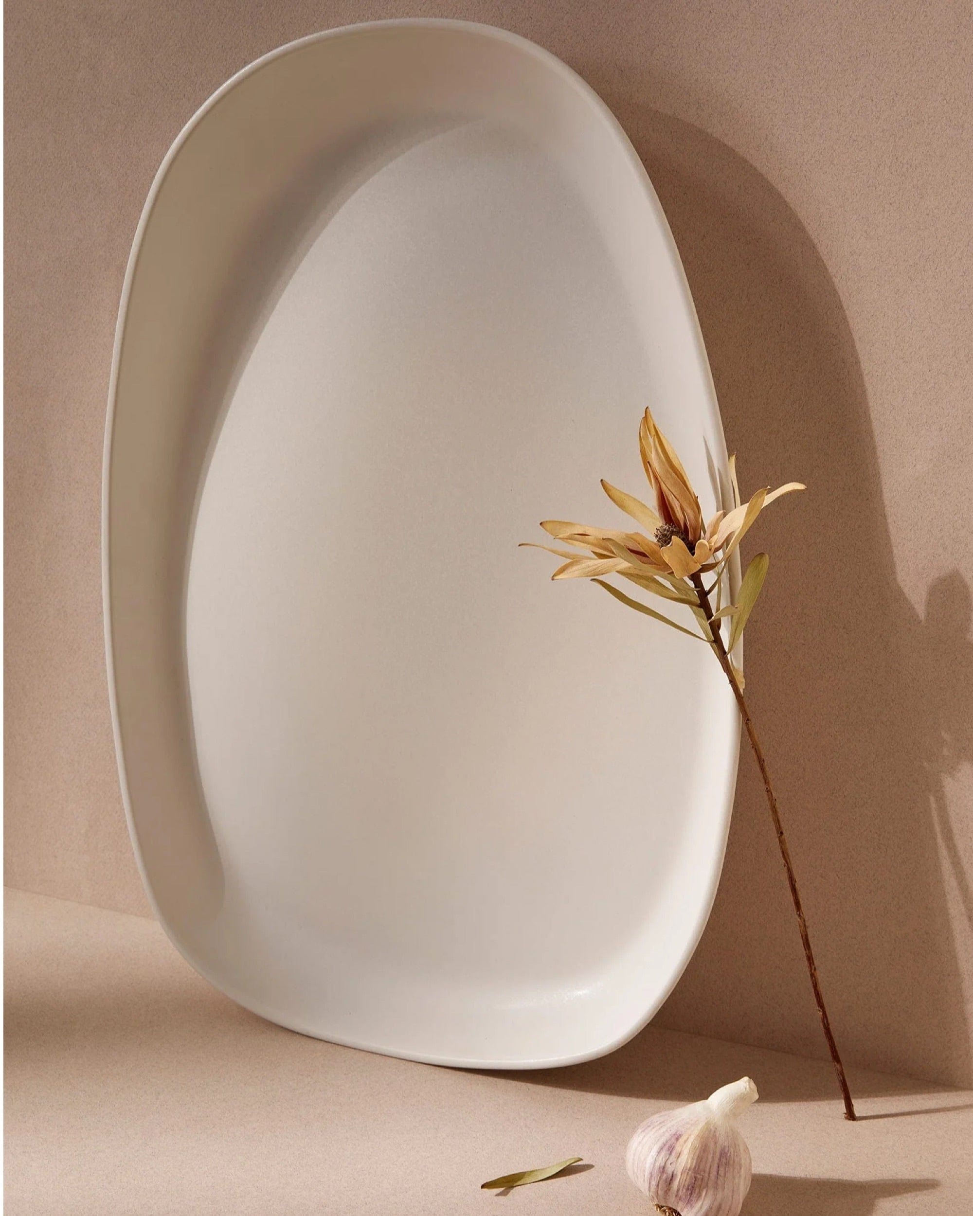Stoneware long serving platter in Matte White with dried branch and garlic
