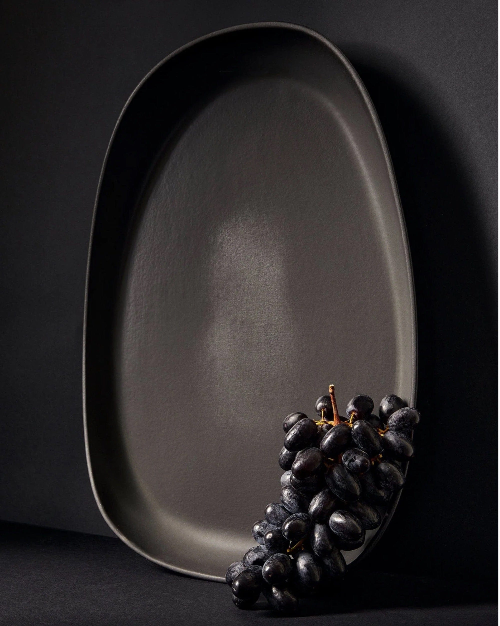Stoneware long serving platter in Matte Black with fresh grapes on dark background