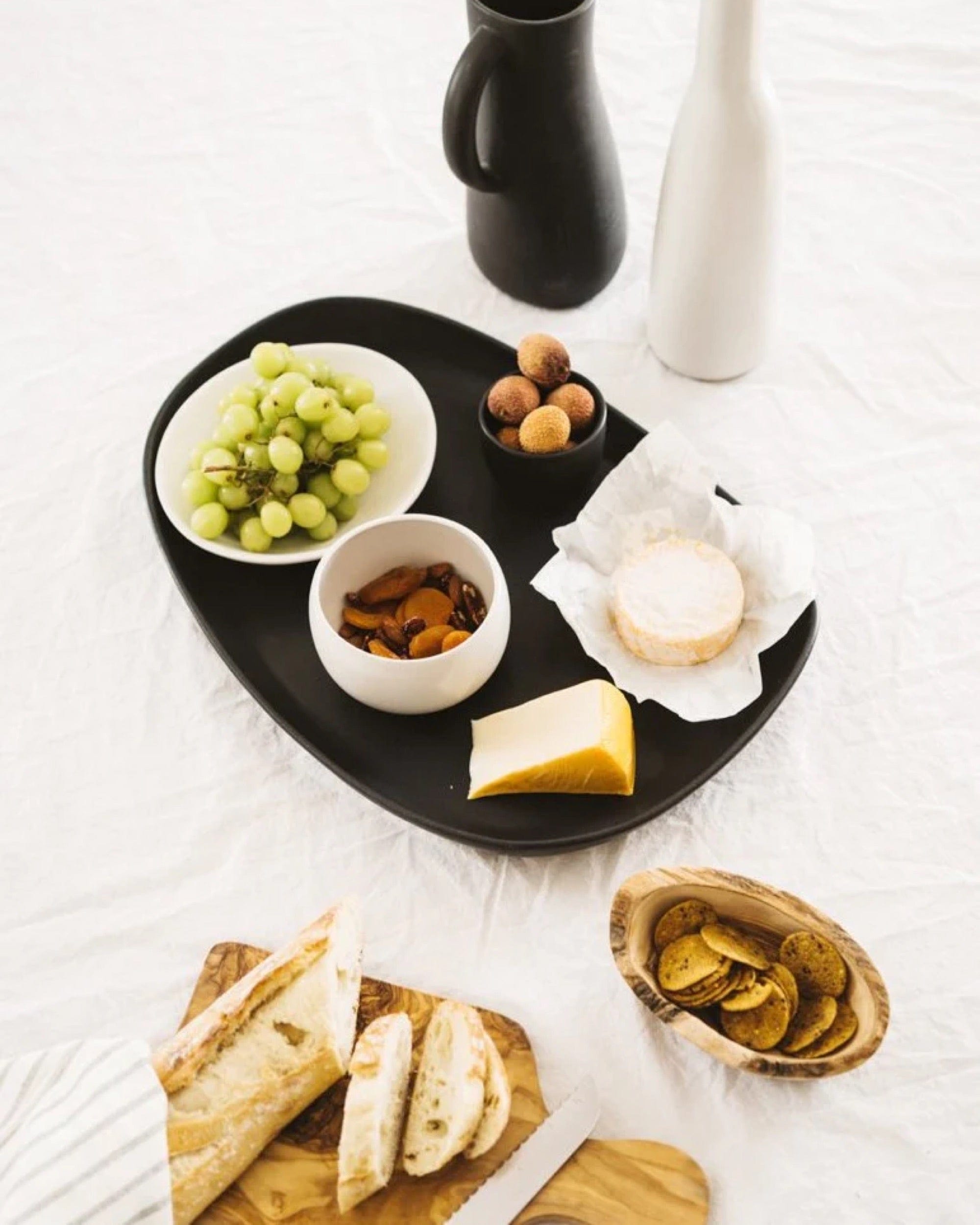 Stoneware long serving platter in Matte Black styled with cheese, grapes, and bread