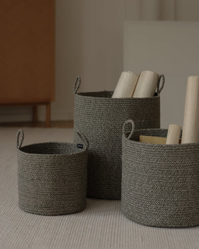 Three basket sizes used together to organize rolled materials in a neutral interior.