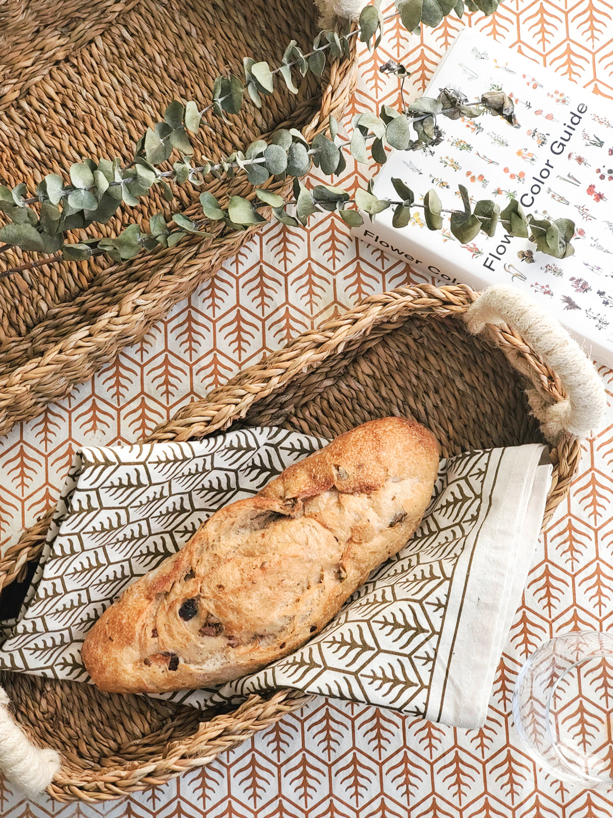 Korissa Hand Screen Printed Tea Towel, light brown print, in seagrass basket with bread