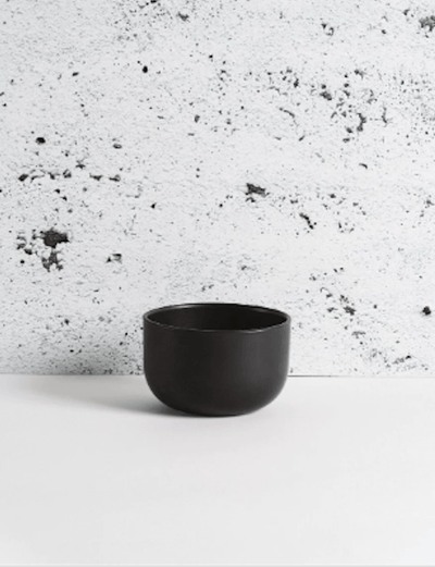 Stoneware bowl in Matte Black against textured concrete background