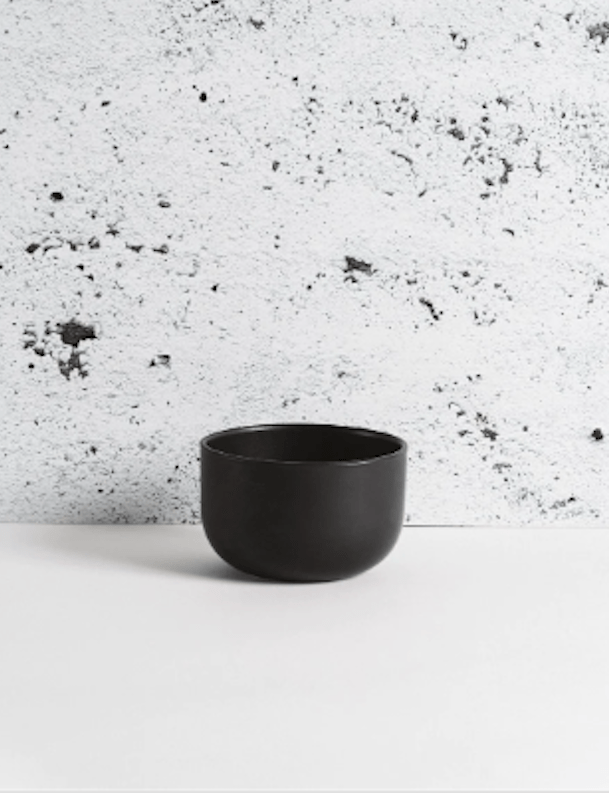 Stoneware bowl in Matte Black against textured concrete background