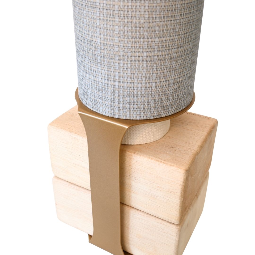 Close-up of the wooden block base secured to the gray tube with a wide tan support strap.