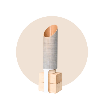 Tall cylindrical yoga mat tube with a gray woven-texture exterior, angled opening, and warm kraft-paper interior, standing on four natural wood blocks.