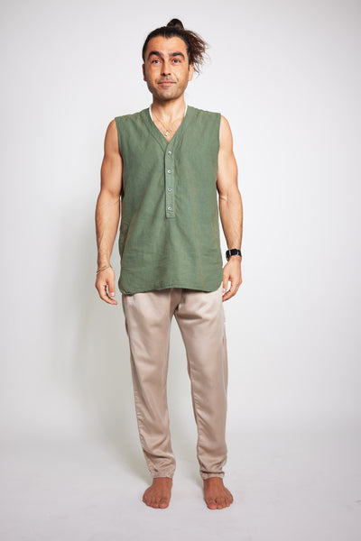 Man standing barefoot in blush Souk cupro silk pants with a sleeveless olive shirt.