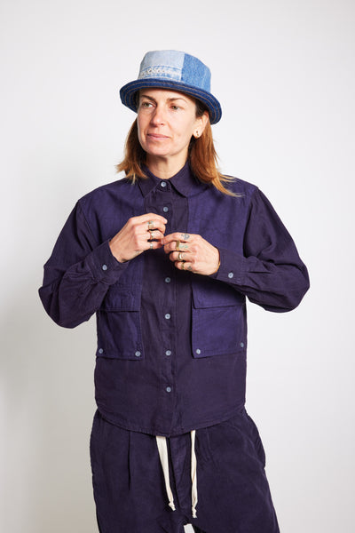 Close front view of a model adjusting the navy Trek Shirt, showing its button closure and utility pockets.