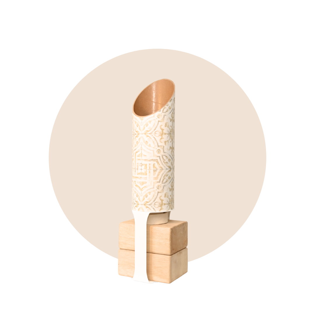 Cream-and-gold patterned cylindrical yoga mat holder standing upright on a four-block natural wood base, framed by a pale beige circle.