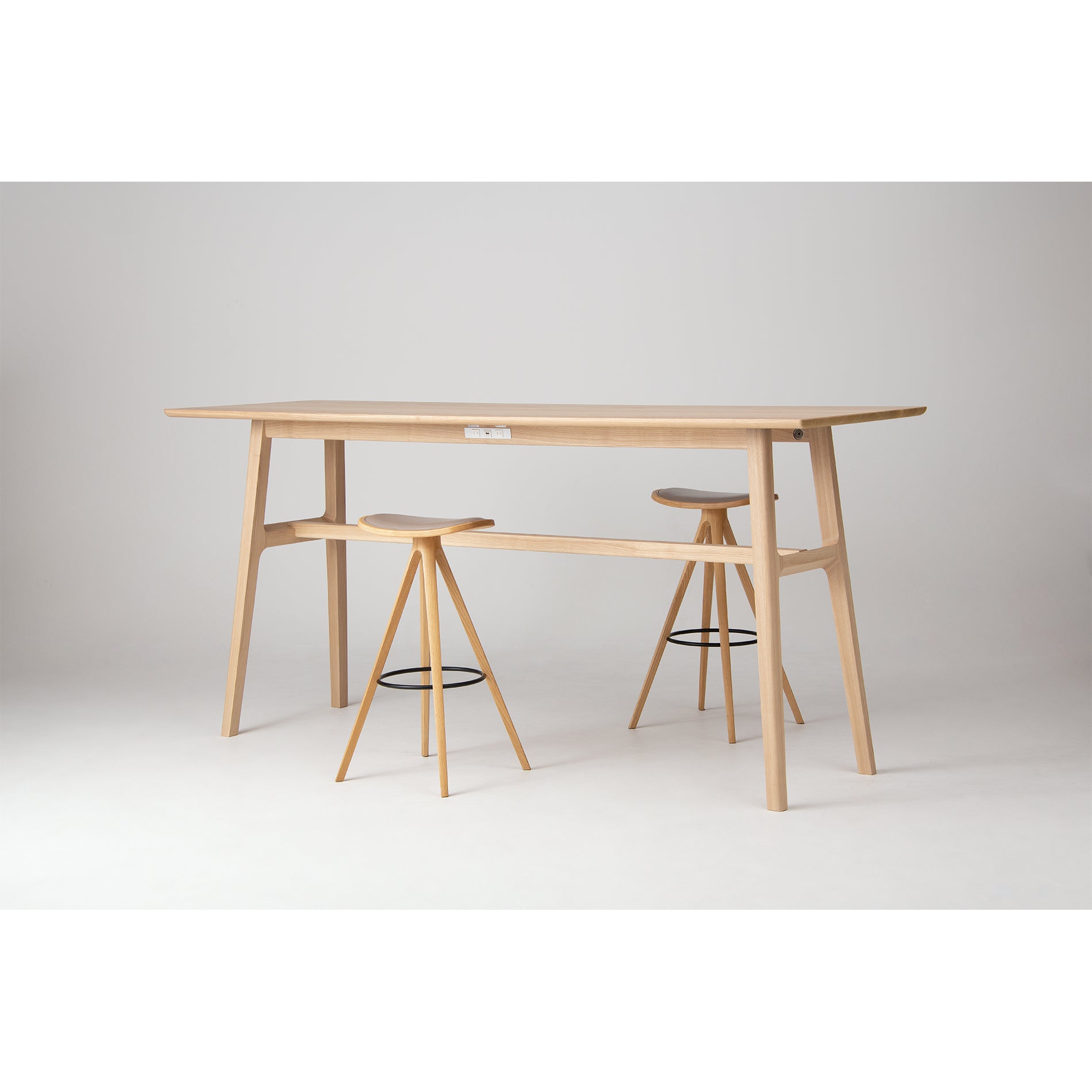 A TEN Bar Height Table with BCTD Wood Stools, photographed in a minimalist studio setting with a neutral gray background.
