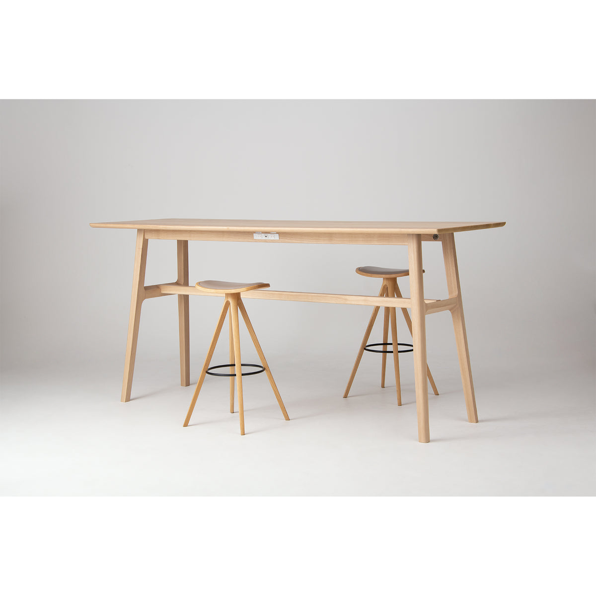 A TEN Bar Height Table with BCTD Wood Stools, photographed in a minimalist studio setting with a neutral gray background.