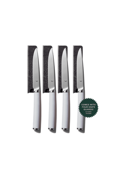 Set of four knives with knife guards on a green background
