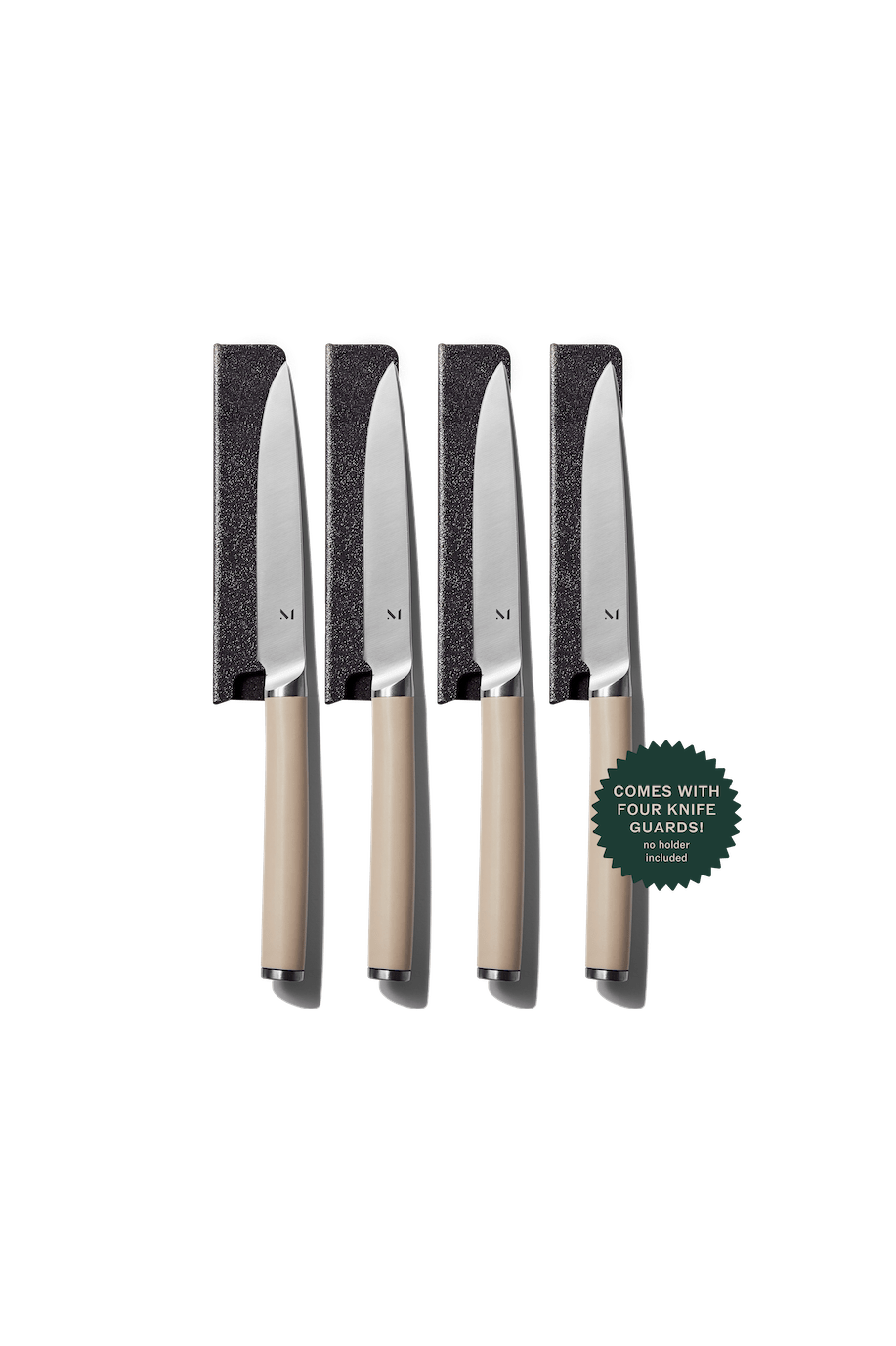 Set of four knives with beige handles and black blade guards on a green background.