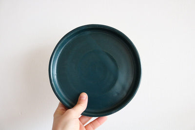 Teal handmade small earthenware plate held in hand