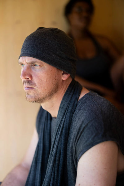 Man wearing a merino wool sauna beanie in a sauna setting, helping provide comfort during heat and recovery sessions.